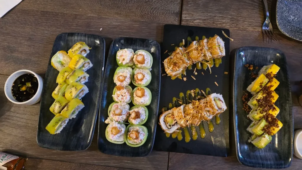 Assorted sushi rolls on black serving plates