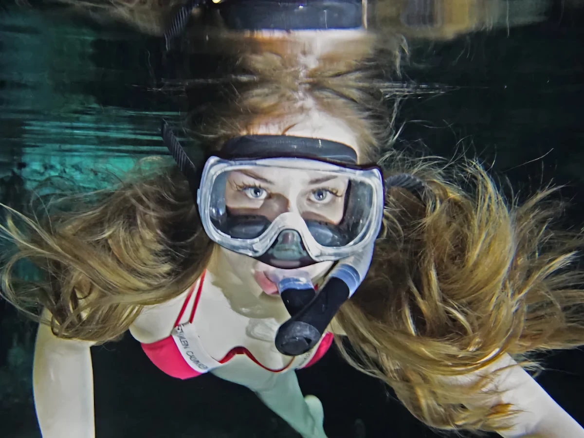 A swimmer underwater wearing a snorkeling mask and snorkel.