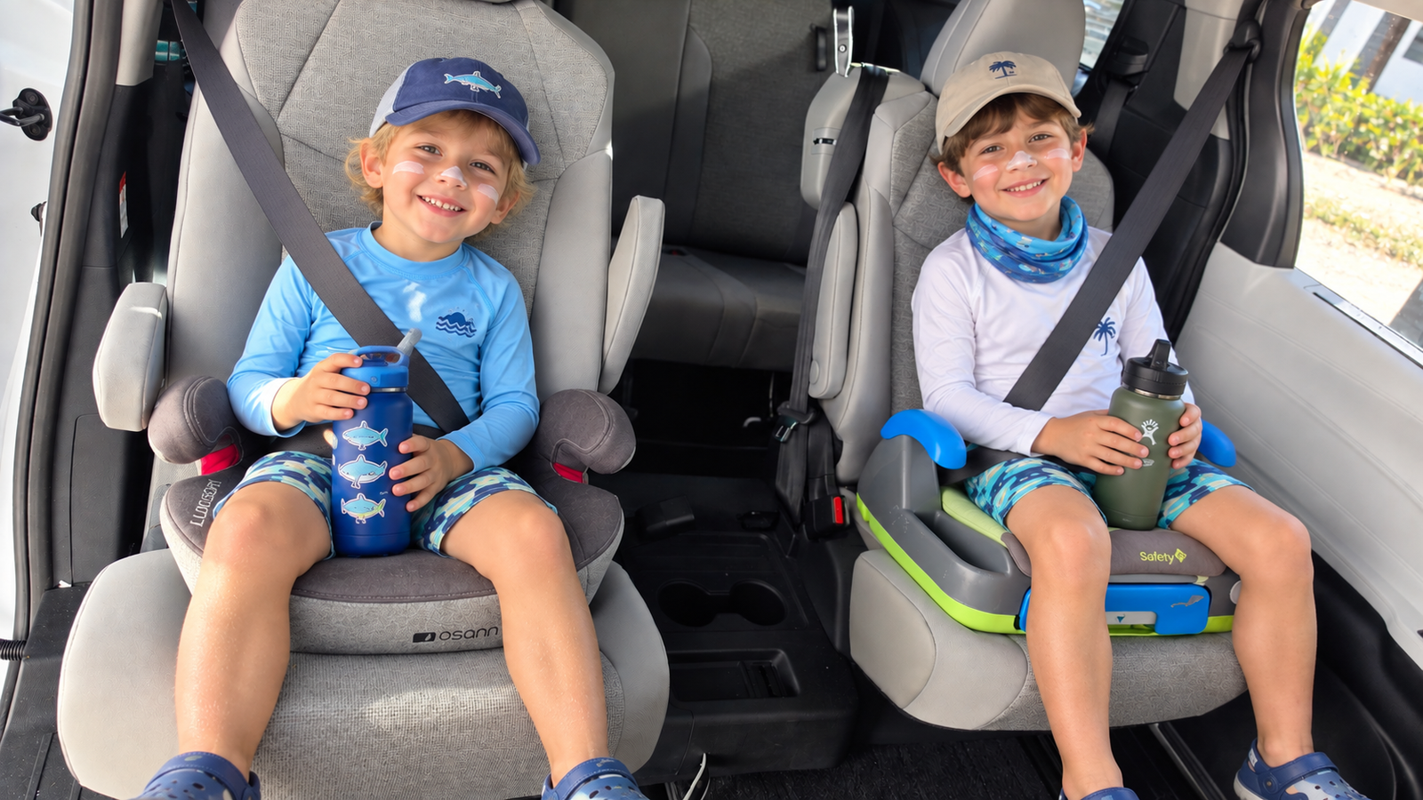 Two children sitting in booster seats inside the van.