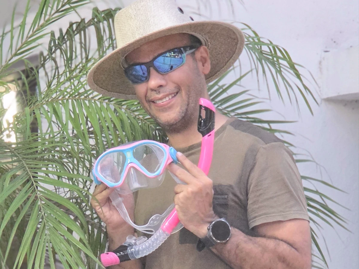 A man holding a pink and blue snorkeling mask and snorkel for children.