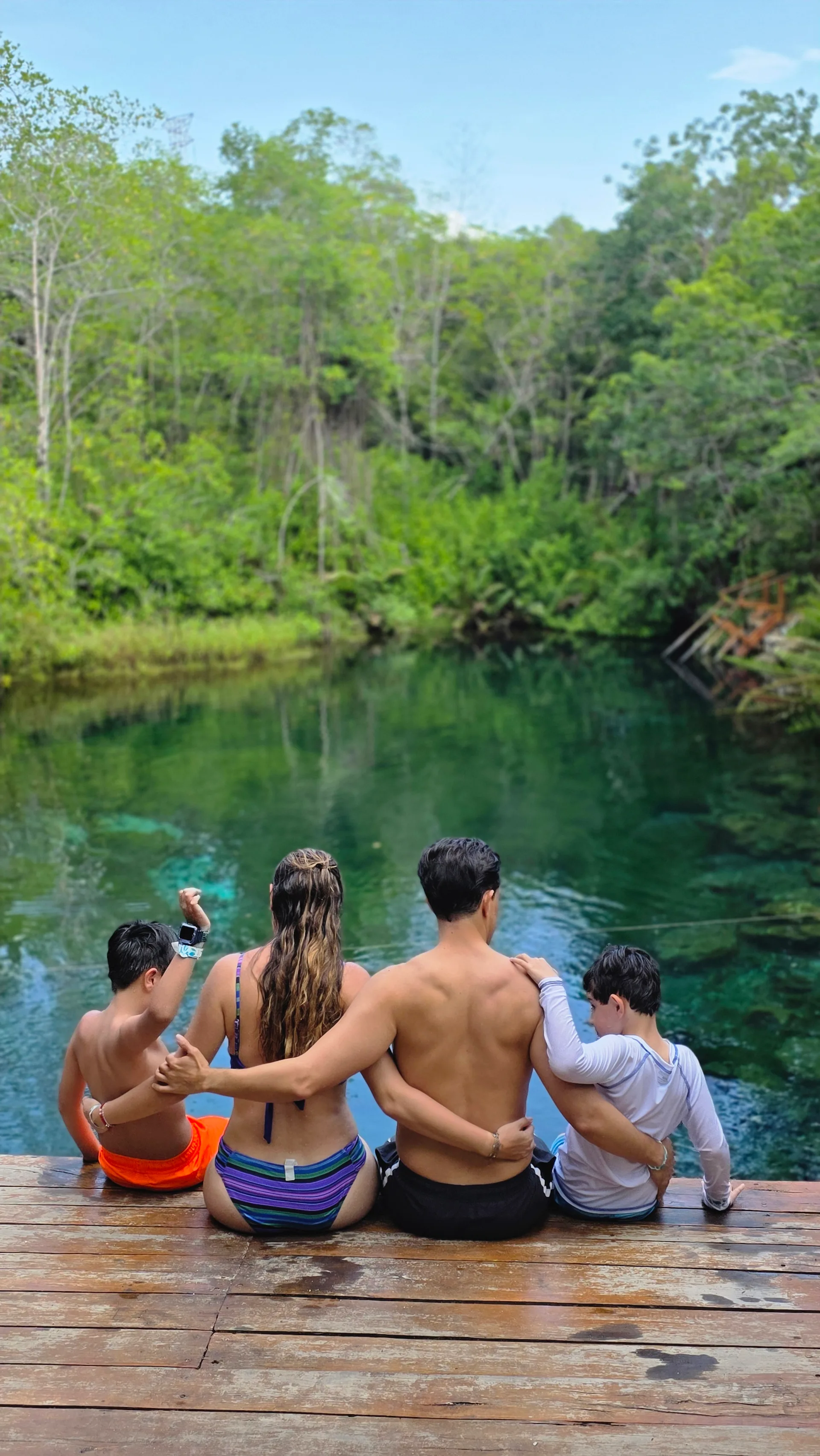 A family sitting together beside a cenote in the Riviera Maya.