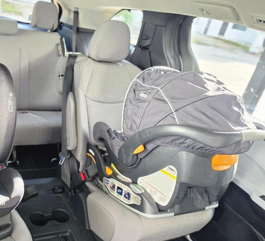 Rear-facing infant carrier on a seat inside our tour vehicle.