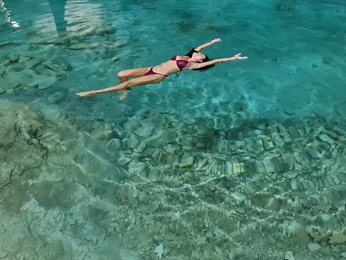 A woman floating peacefully in clear turquoise water.