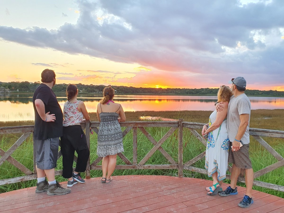 Guests pausing together to enjoy a sunset over a peaceful lake.