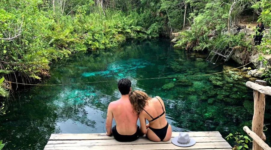A couple enjoying a quiet moment by clear turquoise cenote water