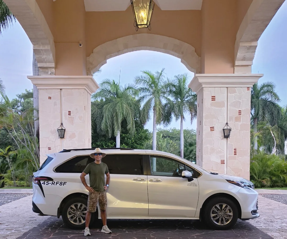 Actual white Toyota Sienna private tour vehicle with its guide in front of a hotel