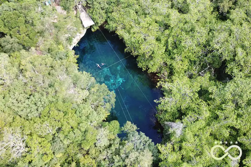 An open cenote surrounded by the Riviera Maya jungle.
